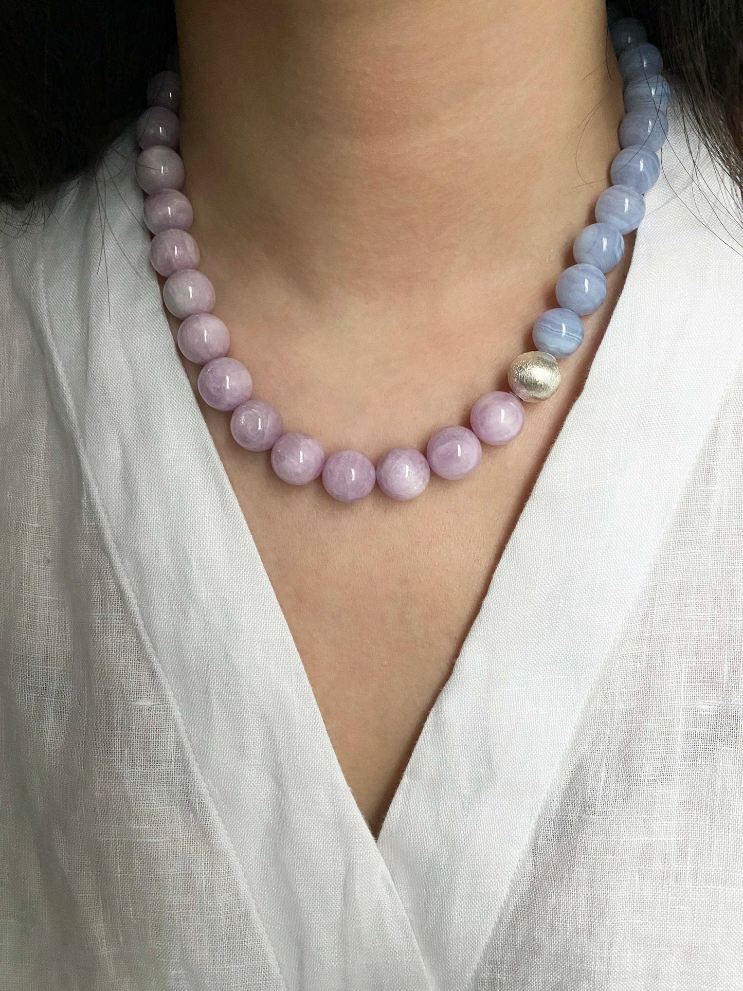 Necklace with pink and purple LaceAgate beads worn by a person in a white shirt