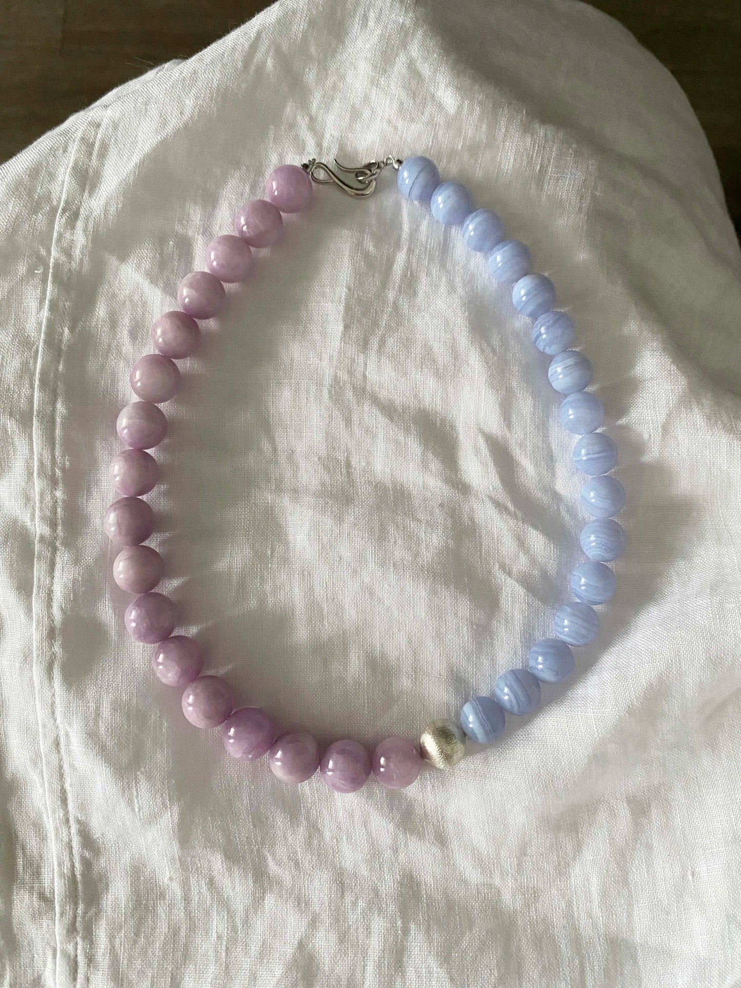 Necklace with purple and blue LaceAgate beads on a white fabric background