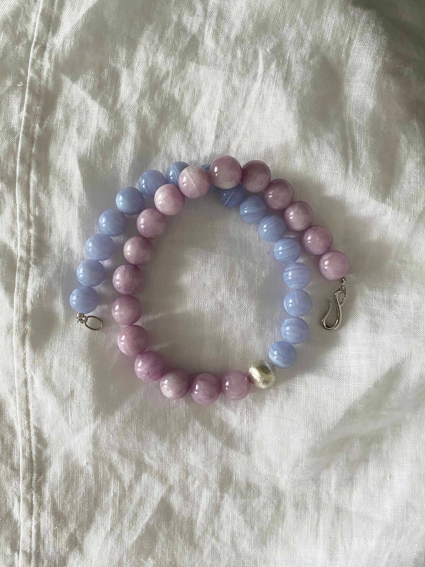 Beaded bracelet with pastel-colored beads on a white fabric background