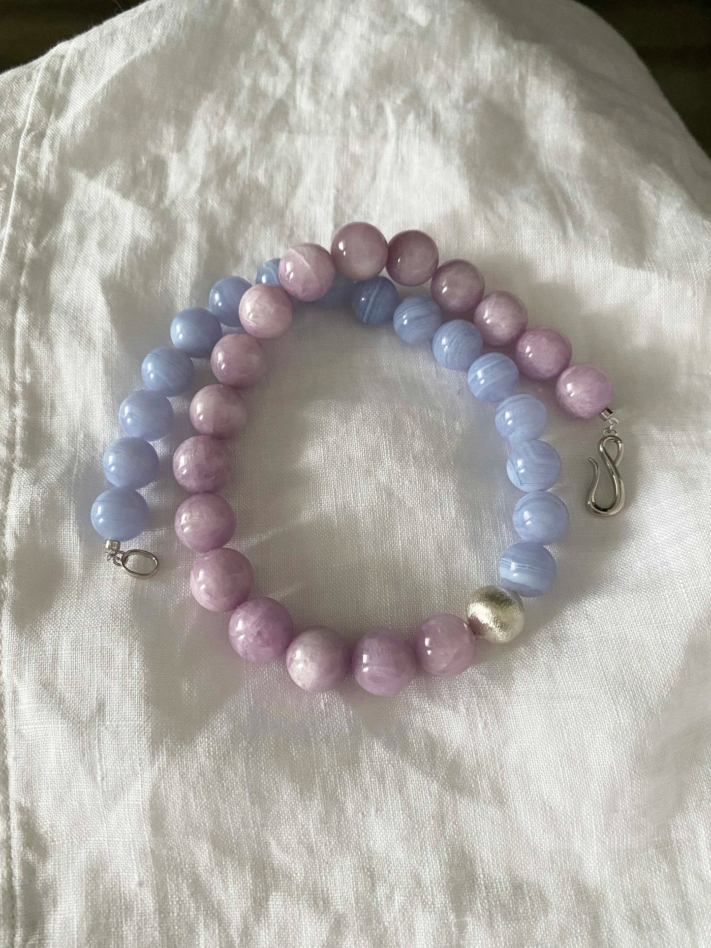 Beaded bracelet with pastel-colored beads on a white fabric background