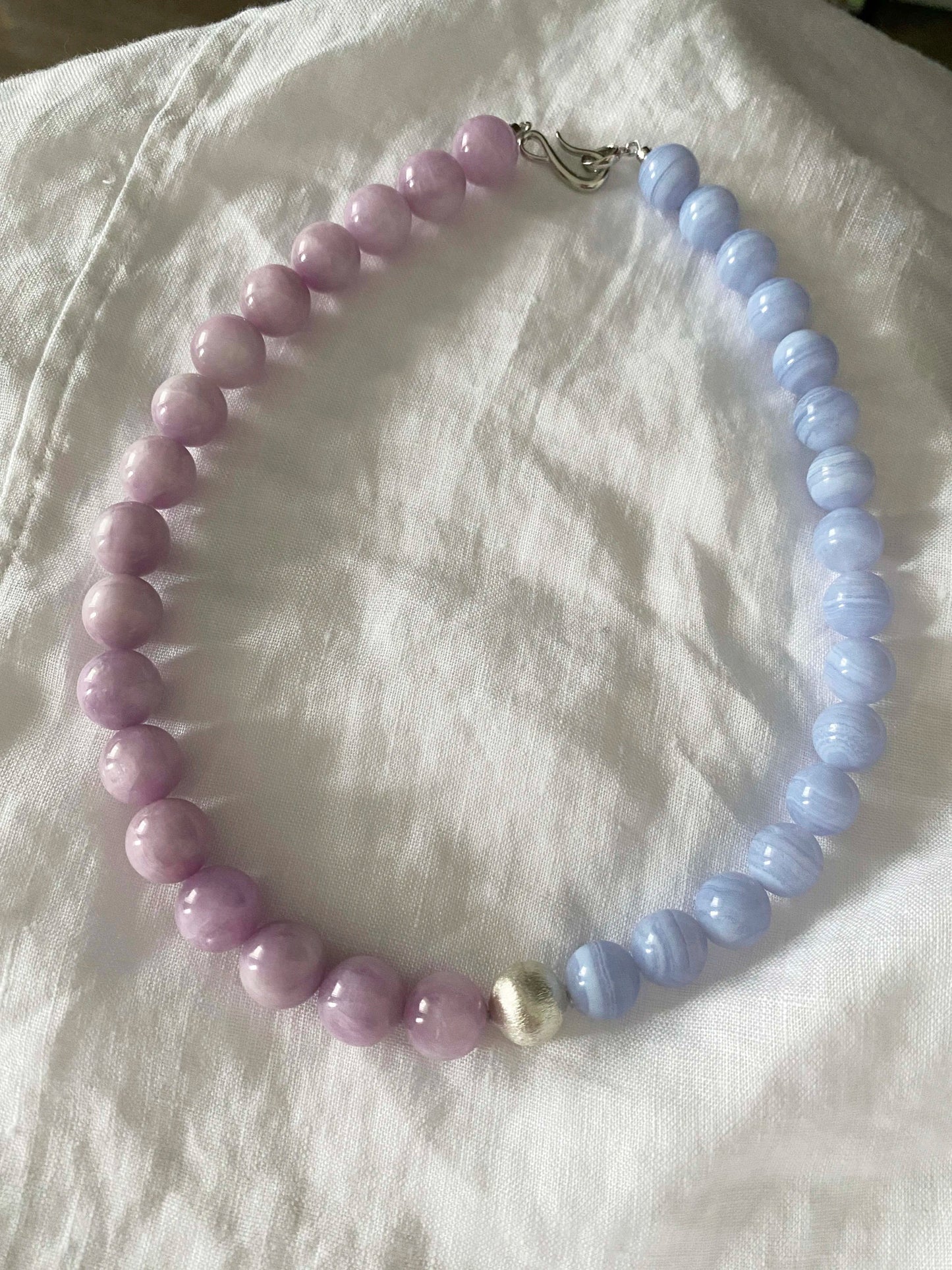 Necklace with pink and blue beads on a white fabric background