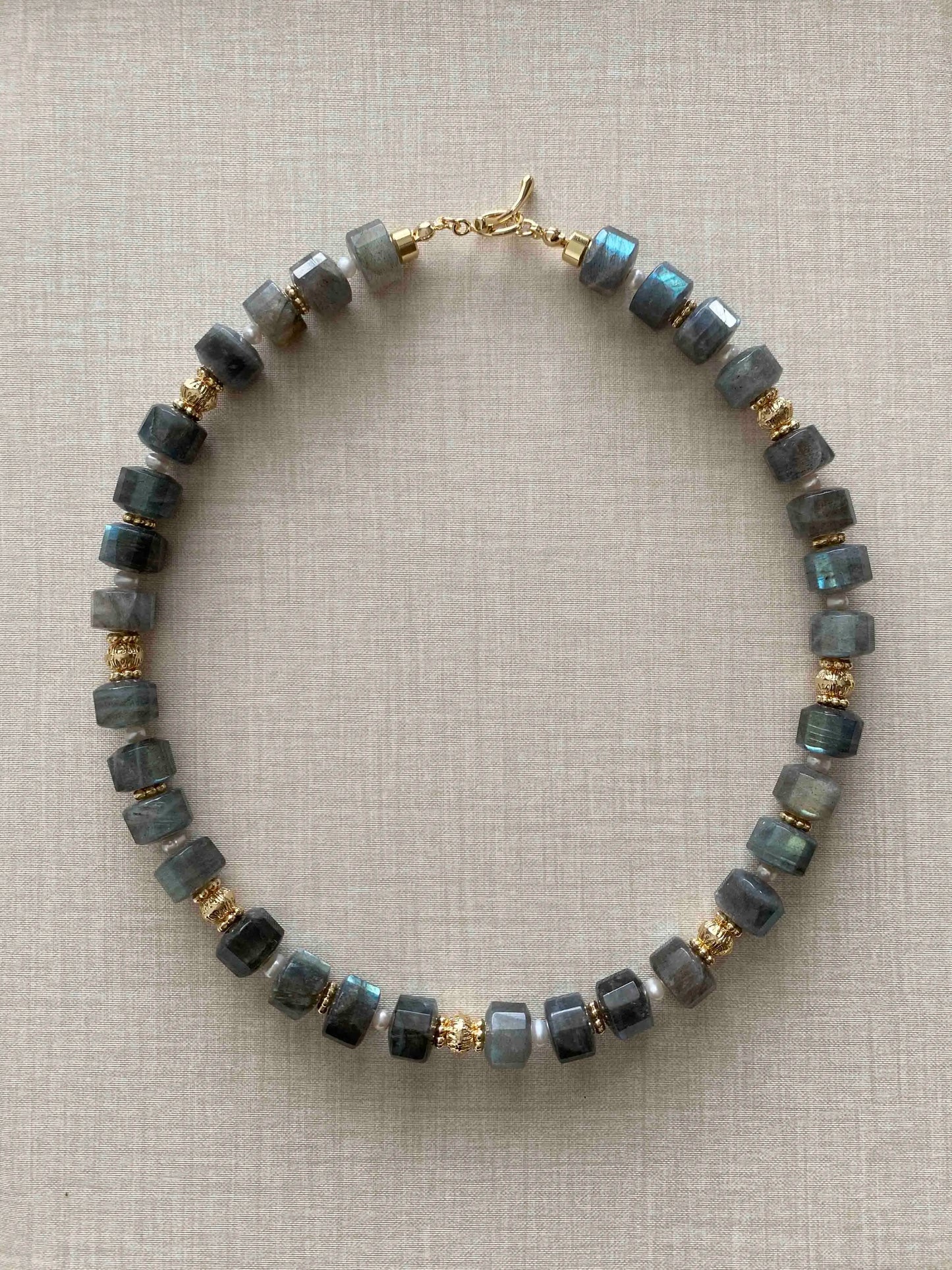 Labradorite Necklace with blue beads and gold accents on a beige background