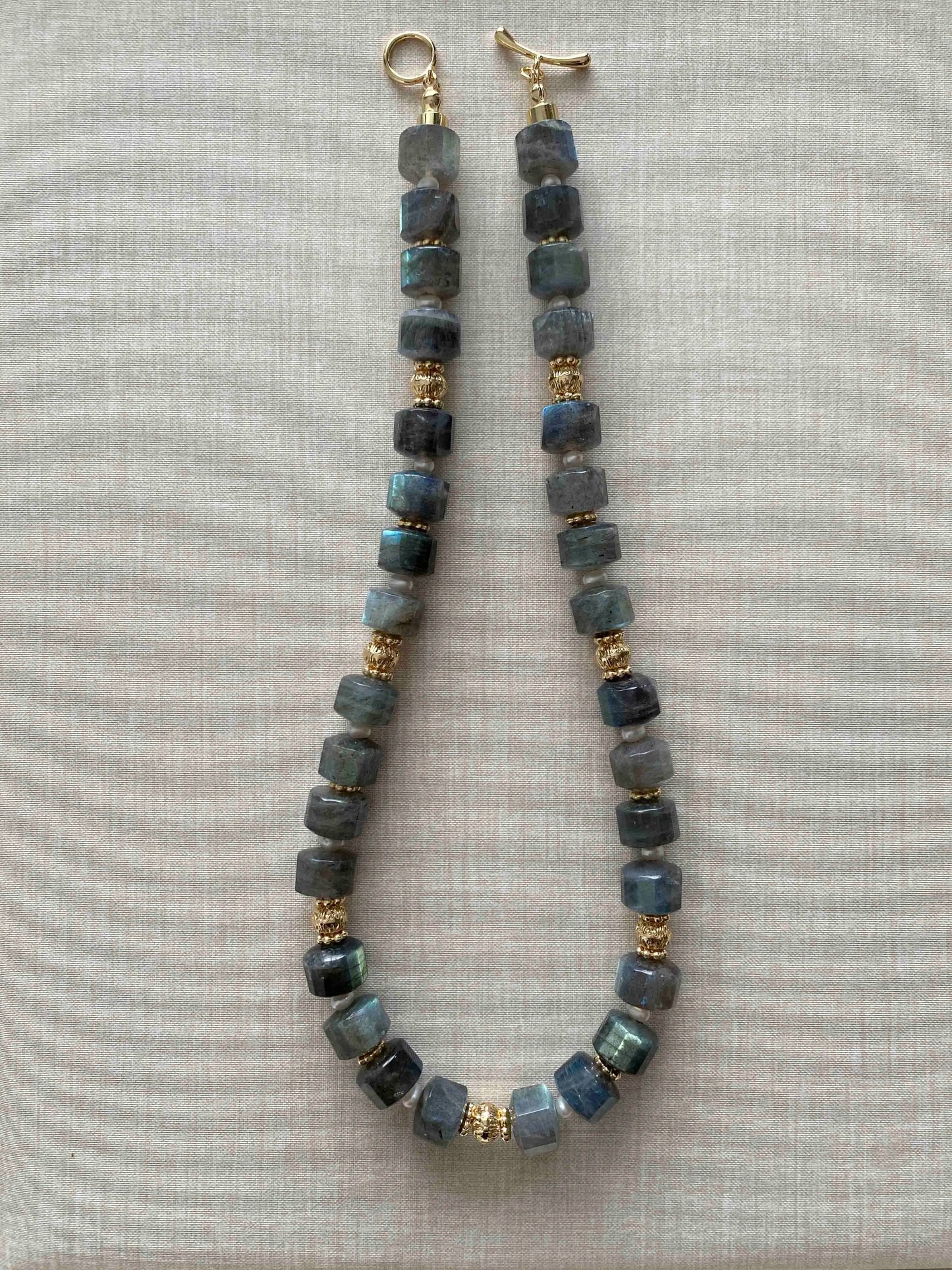Labradorite Necklace with blue beads and gold accents on a light gray background