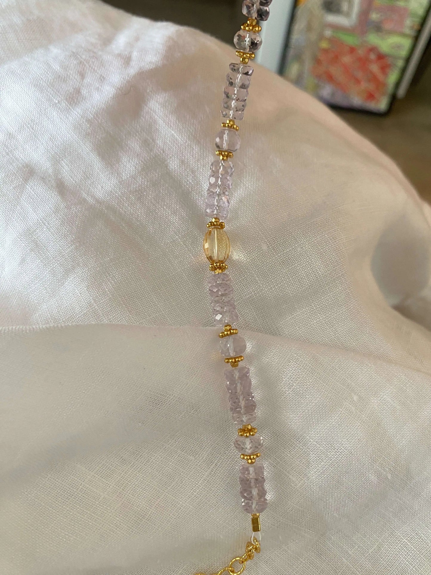 Necklace with 5A Amethyst pink and gold beads on a white fabric background