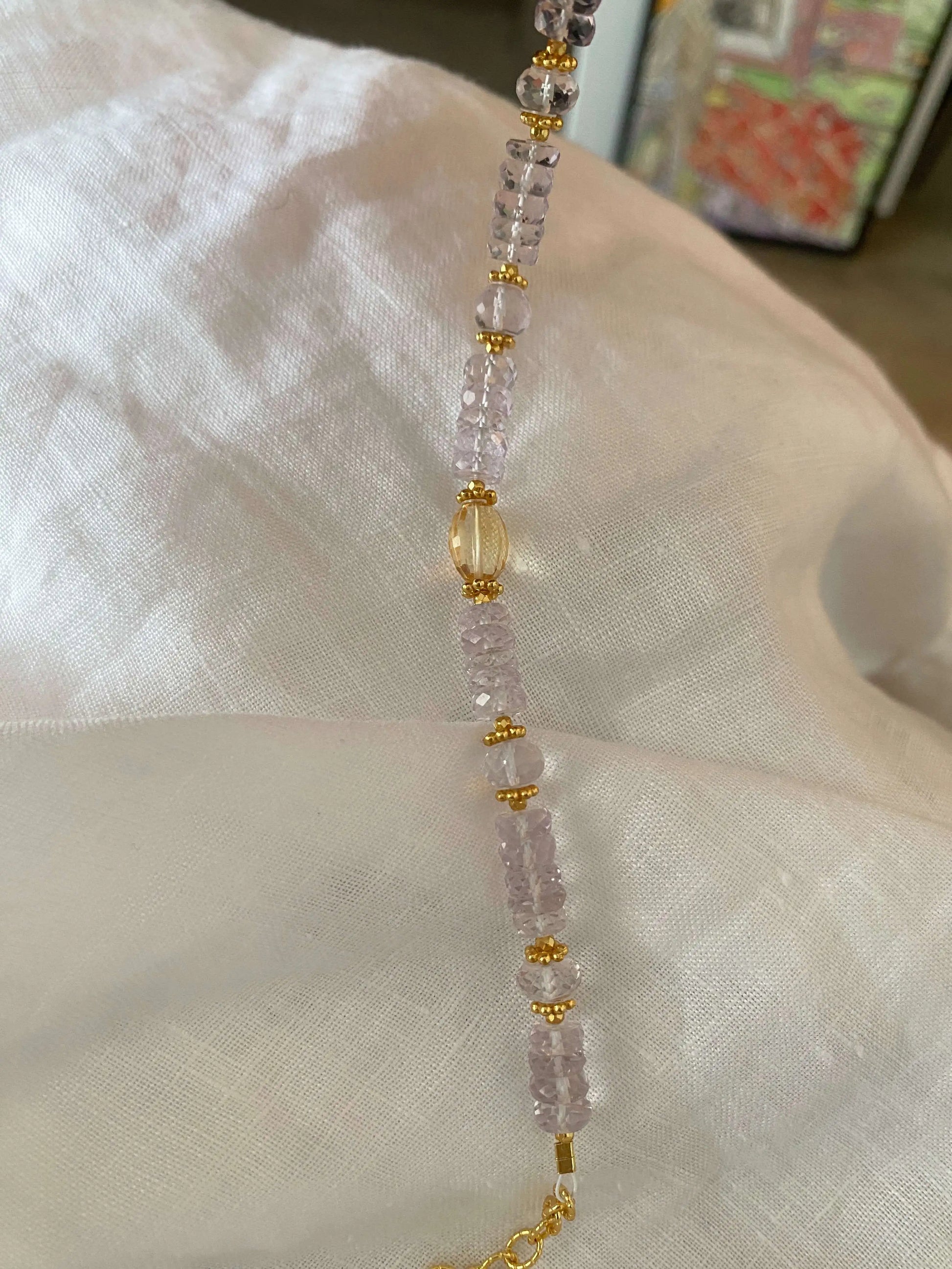 Necklace with 5A Amethyst pink and gold beads on a white fabric background
