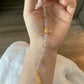 Hand holding a beaded bracelet with gold accents on a neutral background
