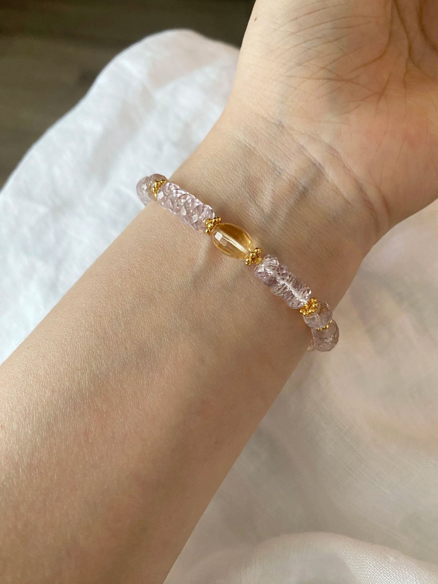 Bracelet with 5A Amethyst pink and gold beads on a wrist against a neutral background